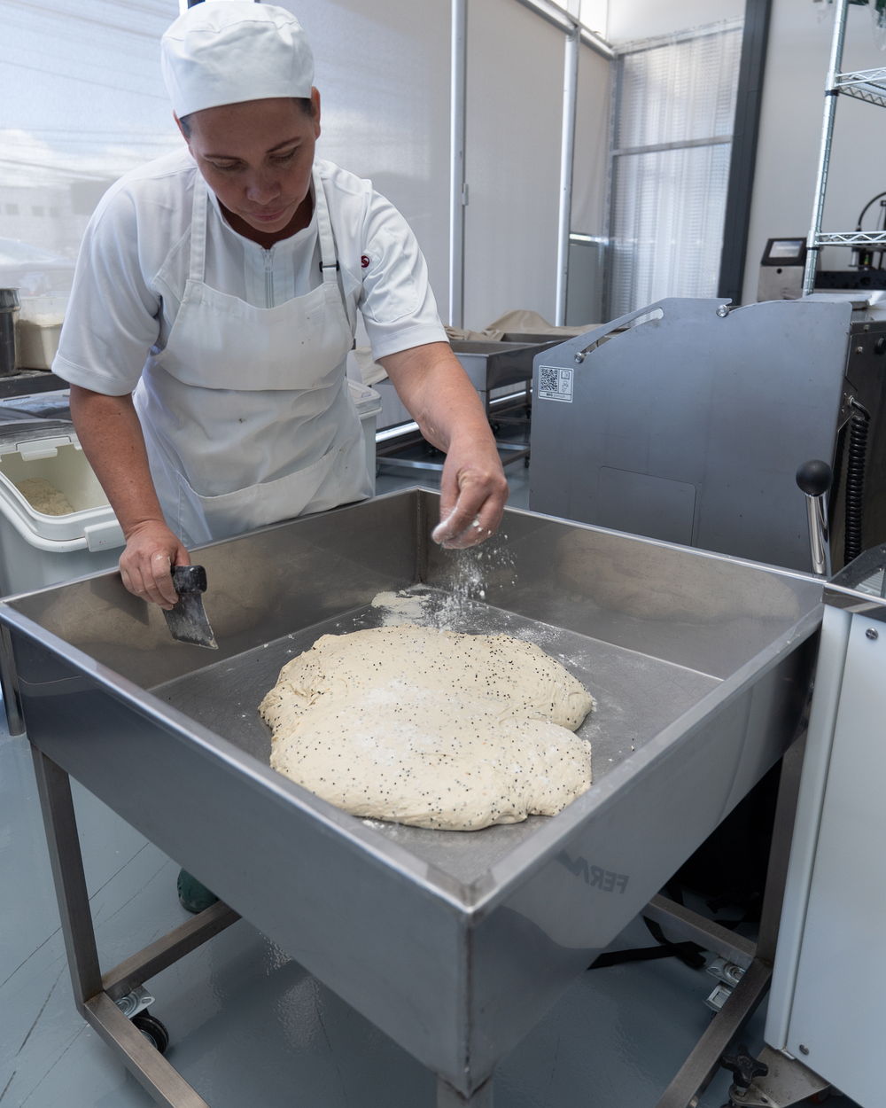 Panadera enharinando la masa en la artesa
